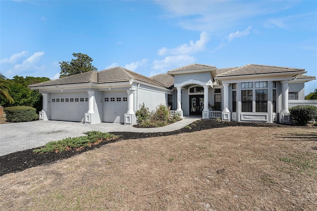 view of front of property with a tiled roof, stucco siding, an attached garage, and decorative driveway