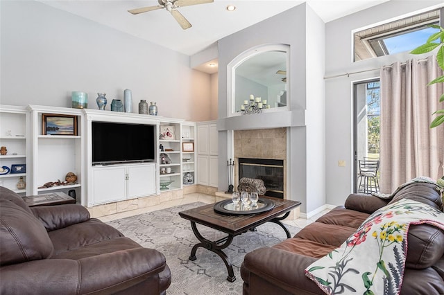 living room featuring a tiled fireplace and ceiling fan