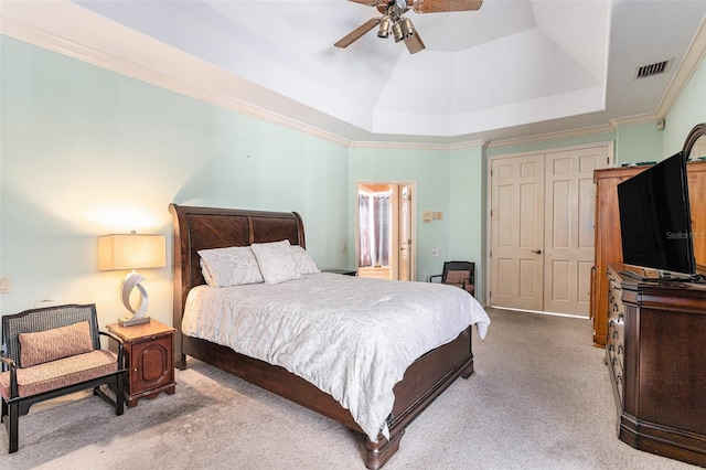 bedroom with a tray ceiling, crown molding, carpet, and visible vents