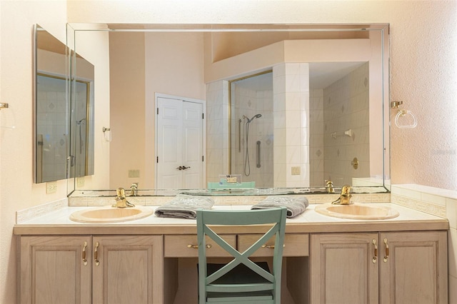 bathroom featuring two vanities, tiled shower, and a sink