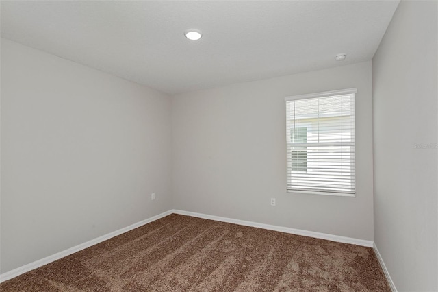 empty room featuring dark carpet and baseboards