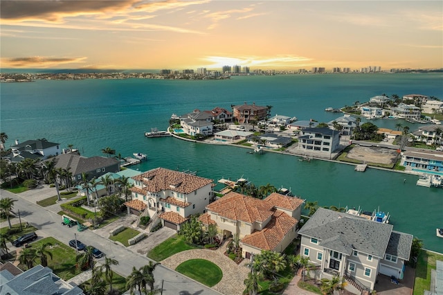 aerial view at dusk featuring a water view and a residential view