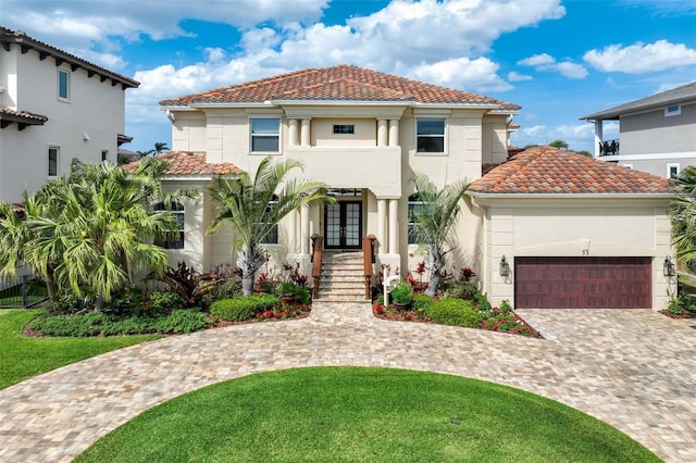 mediterranean / spanish-style house featuring stucco siding, decorative driveway, french doors, a garage, and a tiled roof