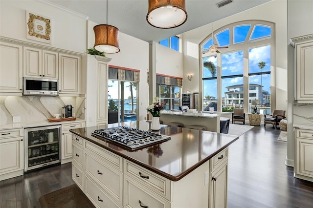 kitchen with dark wood-style floors, stainless steel appliances, wine cooler, cream cabinetry, and backsplash