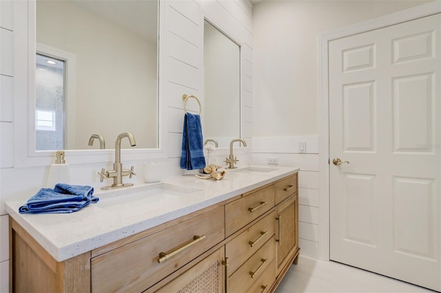 bathroom with double vanity, a wainscoted wall, and a sink