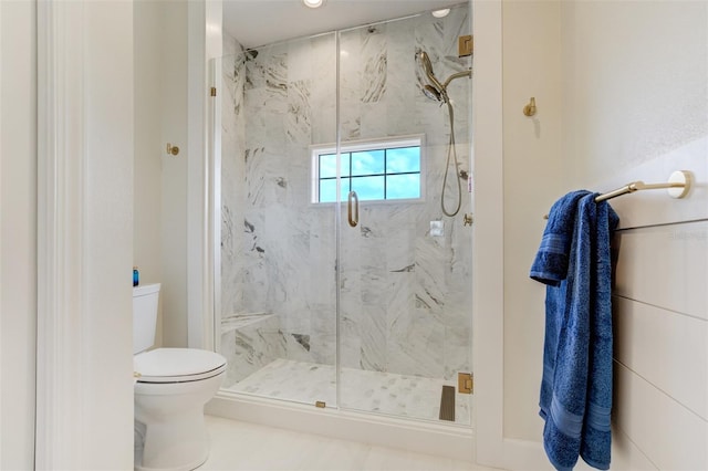 bathroom featuring a marble finish shower and toilet