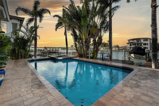 view of swimming pool with a water view, a boat dock, a pool with connected hot tub, boat lift, and a patio area