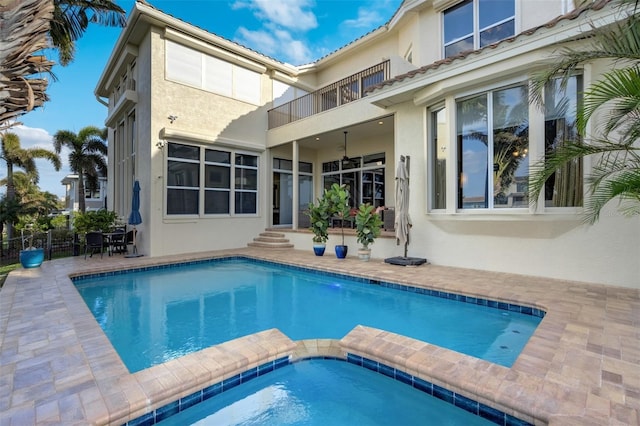 rear view of house with a balcony, fence, ceiling fan, stucco siding, and a patio area