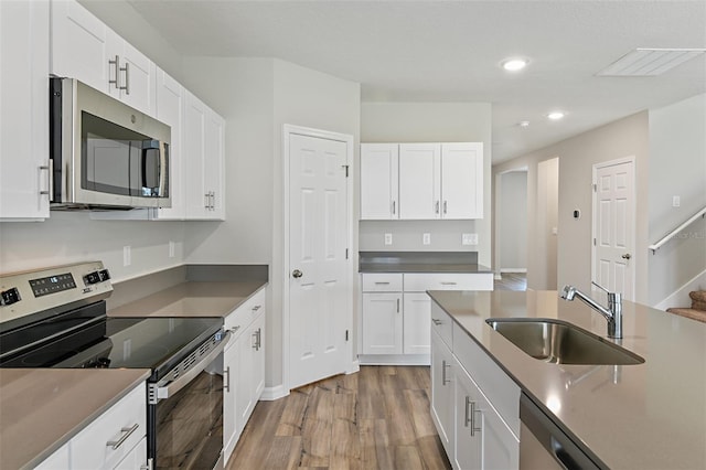 kitchen featuring light wood-type flooring, visible vents, a sink, appliances with stainless steel finishes, and white cabinets