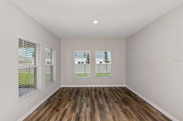 unfurnished room with baseboards and dark wood-style flooring