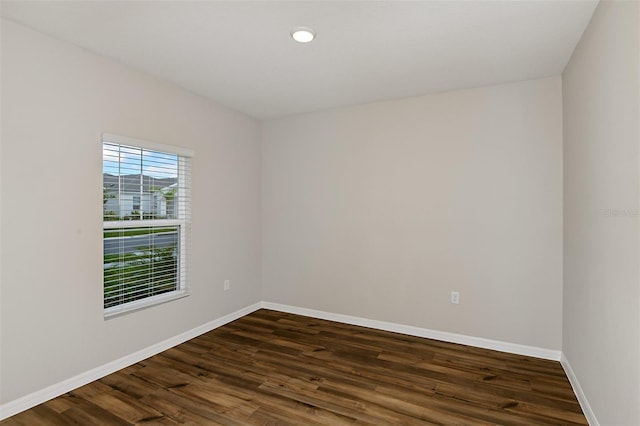 empty room featuring recessed lighting, dark wood-type flooring, and baseboards