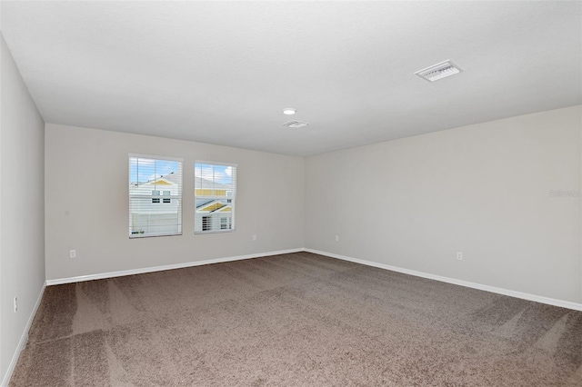 unfurnished room featuring visible vents, baseboards, and dark colored carpet