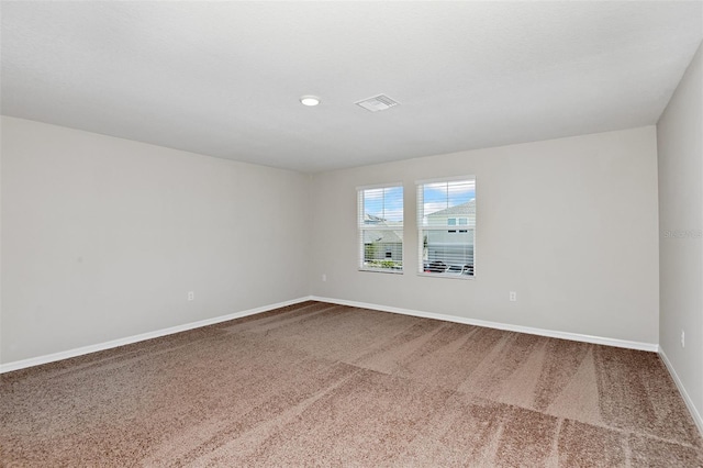 carpeted spare room featuring visible vents and baseboards