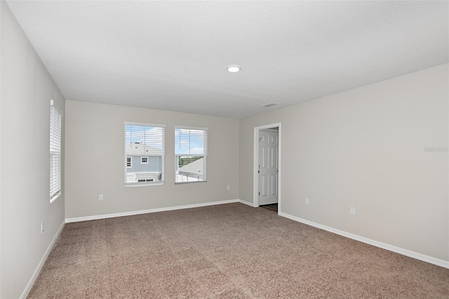 carpeted spare room featuring visible vents and baseboards