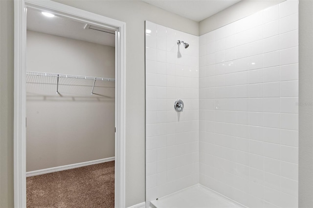 full bath with a walk in closet, tiled shower, and baseboards