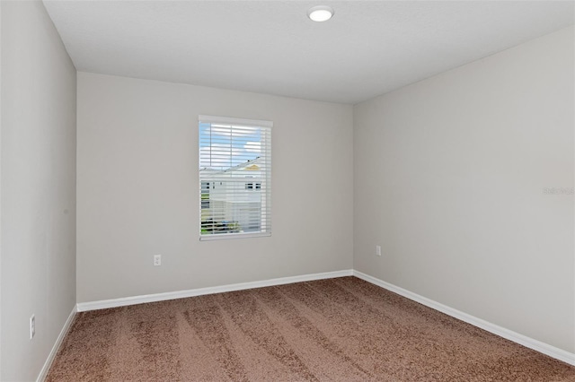 carpeted empty room featuring baseboards