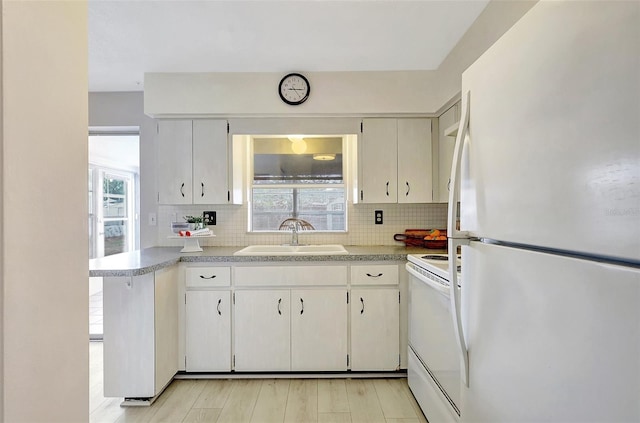 kitchen with a sink, white appliances, tasteful backsplash, and light countertops