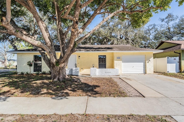 ranch-style house featuring an attached garage, driveway, and fence