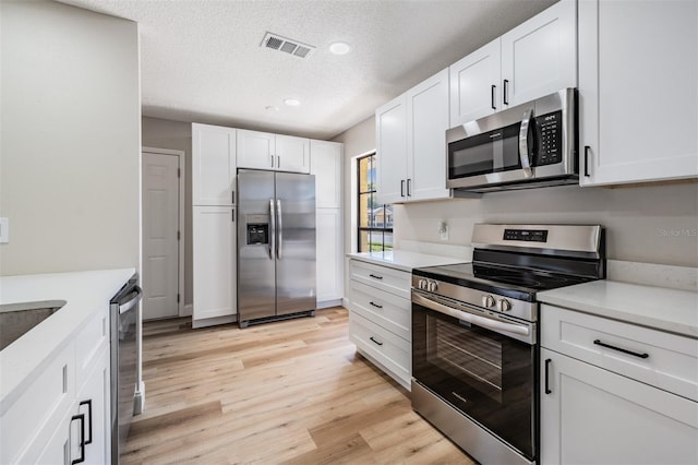 kitchen featuring visible vents, white cabinetry, and stainless steel appliances