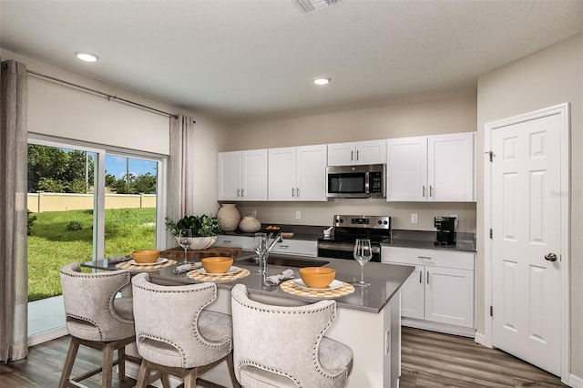 kitchen featuring a sink, dark countertops, dark wood-style floors, white cabinetry, and stainless steel appliances