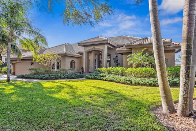 mediterranean / spanish home with stucco siding, a garage, a front lawn, and a tiled roof