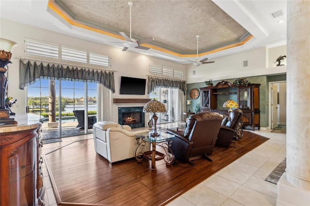 living room featuring a raised ceiling, a ceiling fan, and visible vents