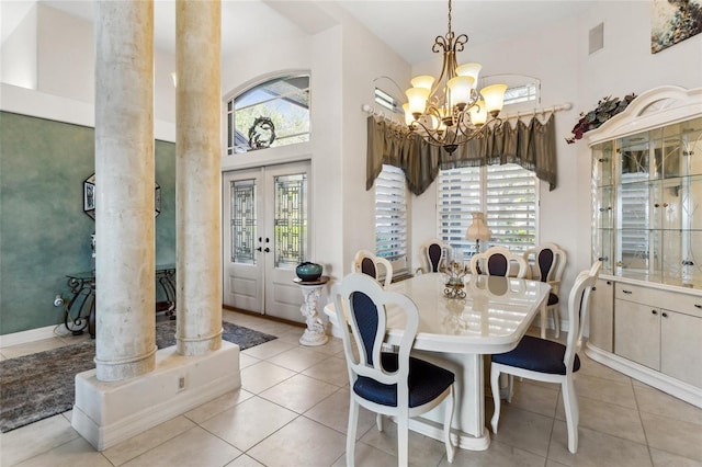 dining room featuring an inviting chandelier, light tile patterned flooring, ornate columns, and a towering ceiling