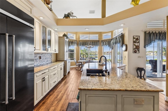 kitchen featuring high end black refrigerator, plenty of natural light, wood finished floors, and a sink