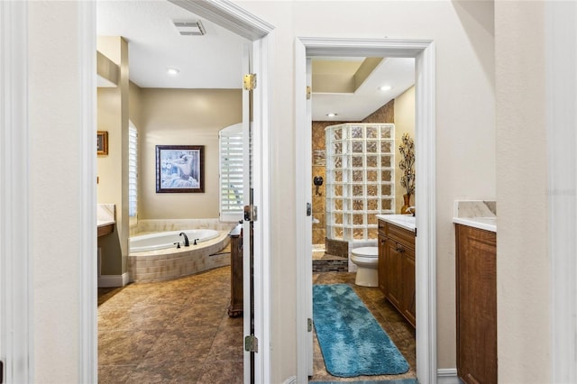 bathroom featuring visible vents, toilet, a tile shower, a bath, and vanity