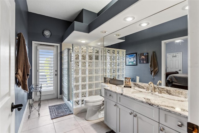 ensuite bathroom featuring tile patterned flooring, toilet, vanity, and walk in shower