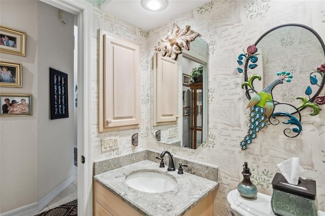 bathroom featuring vanity, baseboards, and wallpapered walls