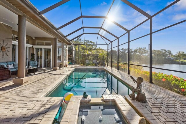 view of swimming pool with a patio area, glass enclosure, a pool with connected hot tub, and a water view