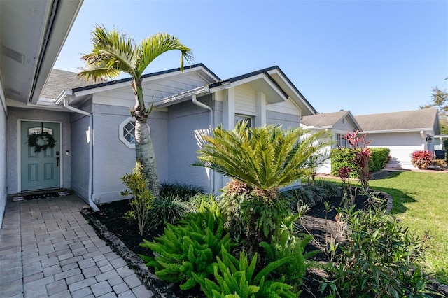 view of side of property featuring an attached garage, a yard, and stucco siding