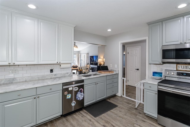 kitchen with a sink, appliances with stainless steel finishes, light wood-style flooring, and gray cabinets