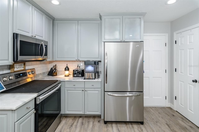 kitchen featuring tasteful backsplash, appliances with stainless steel finishes, light wood-style flooring, and gray cabinetry