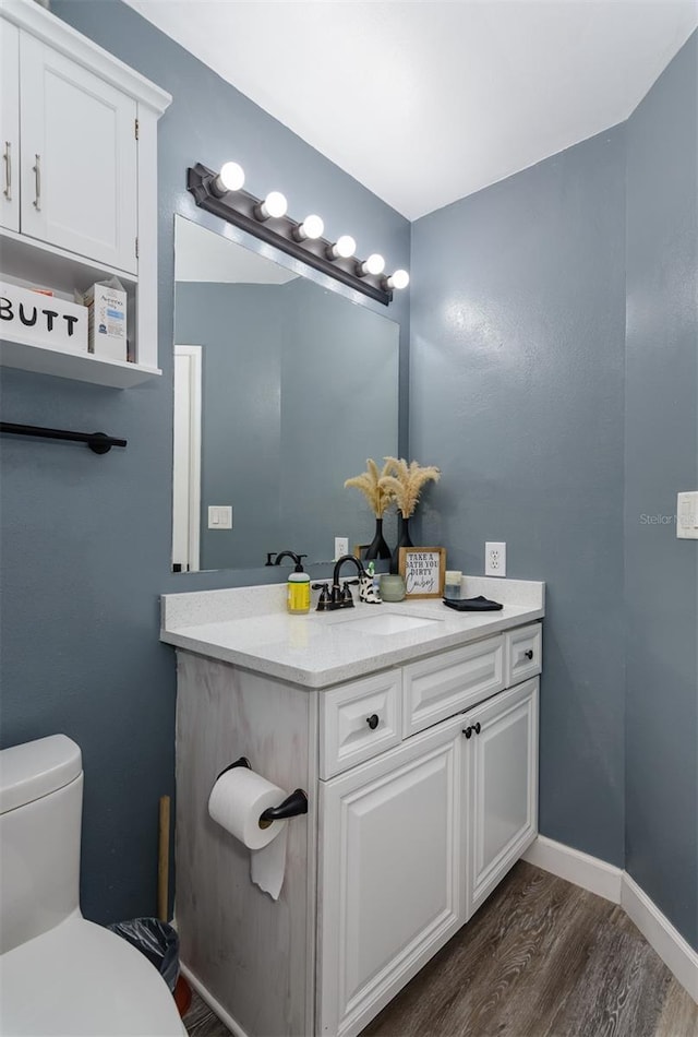 bathroom with baseboards, toilet, wood finished floors, and vanity