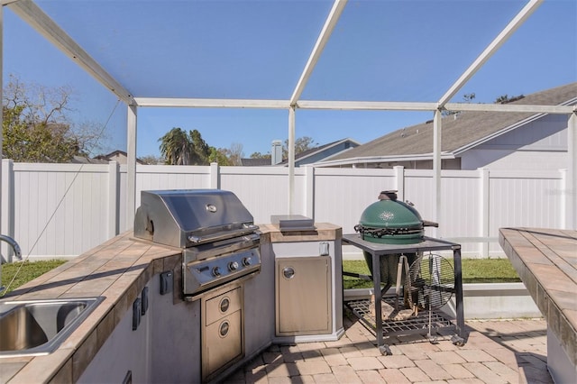 view of patio with exterior kitchen, grilling area, a fenced backyard, and a sink