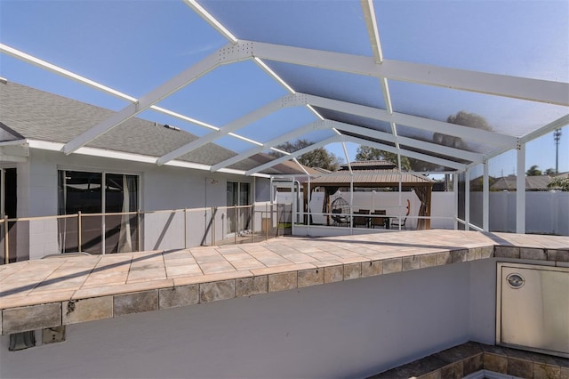 view of patio / terrace featuring glass enclosure, a gazebo, and fence