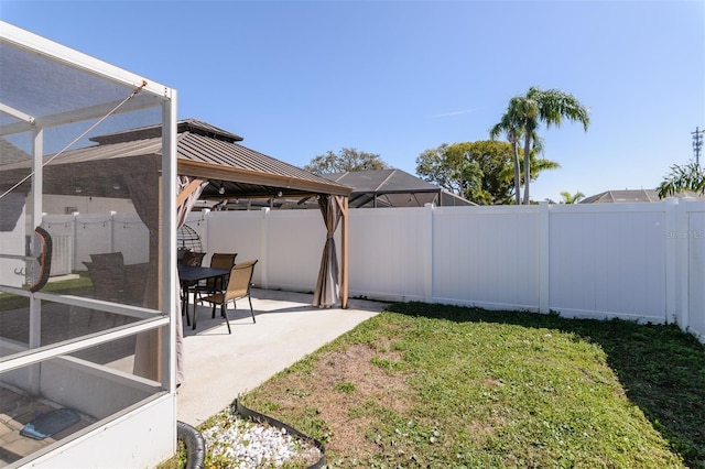 view of yard featuring glass enclosure, a gazebo, a patio area, and a fenced backyard