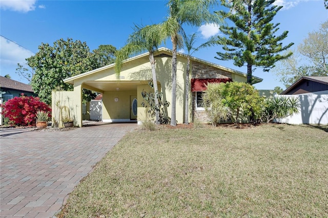 view of front of property with stucco siding, decorative driveway, a front lawn, and fence