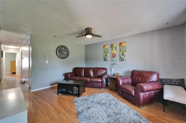 living room featuring ceiling fan, visible vents, a textured ceiling, and wood finished floors