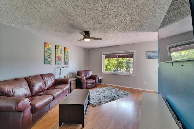 living room with light wood-type flooring, baseboards, a textured ceiling, and a ceiling fan