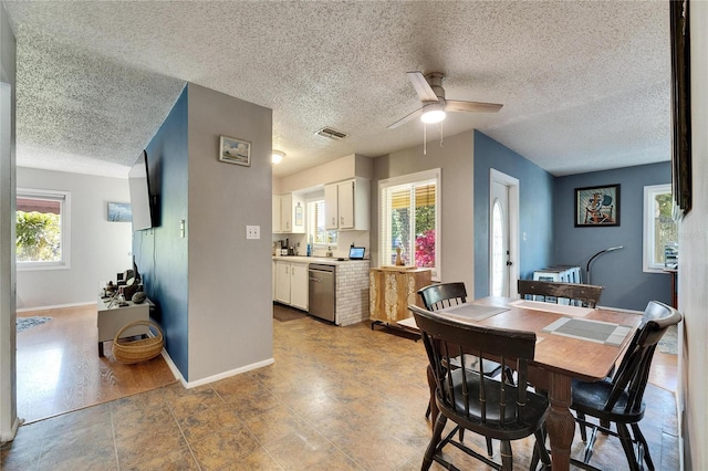 dining area with a ceiling fan, baseboards, visible vents, and a textured ceiling