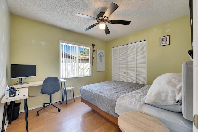 bedroom with a closet, baseboards, a textured ceiling, and wood finished floors