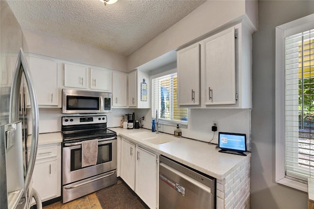 kitchen with white cabinets, stainless steel appliances, light countertops, and a sink