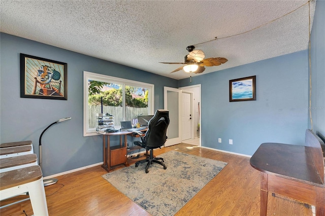 office space with baseboards, a textured ceiling, wood finished floors, and a ceiling fan