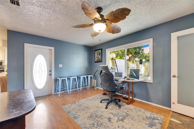 office area with baseboards, wood finished floors, visible vents, and a textured ceiling