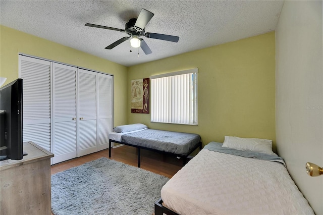 bedroom featuring ceiling fan, a closet, a textured ceiling, and wood finished floors