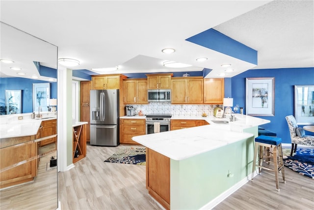 kitchen featuring a sink, a peninsula, backsplash, and stainless steel appliances