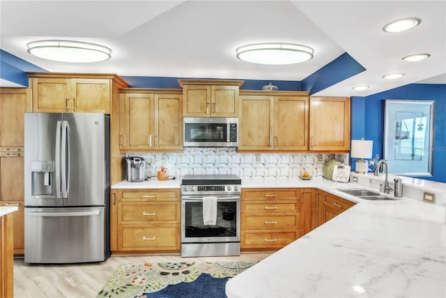 kitchen featuring a sink, light countertops, light wood-style flooring, and stainless steel appliances